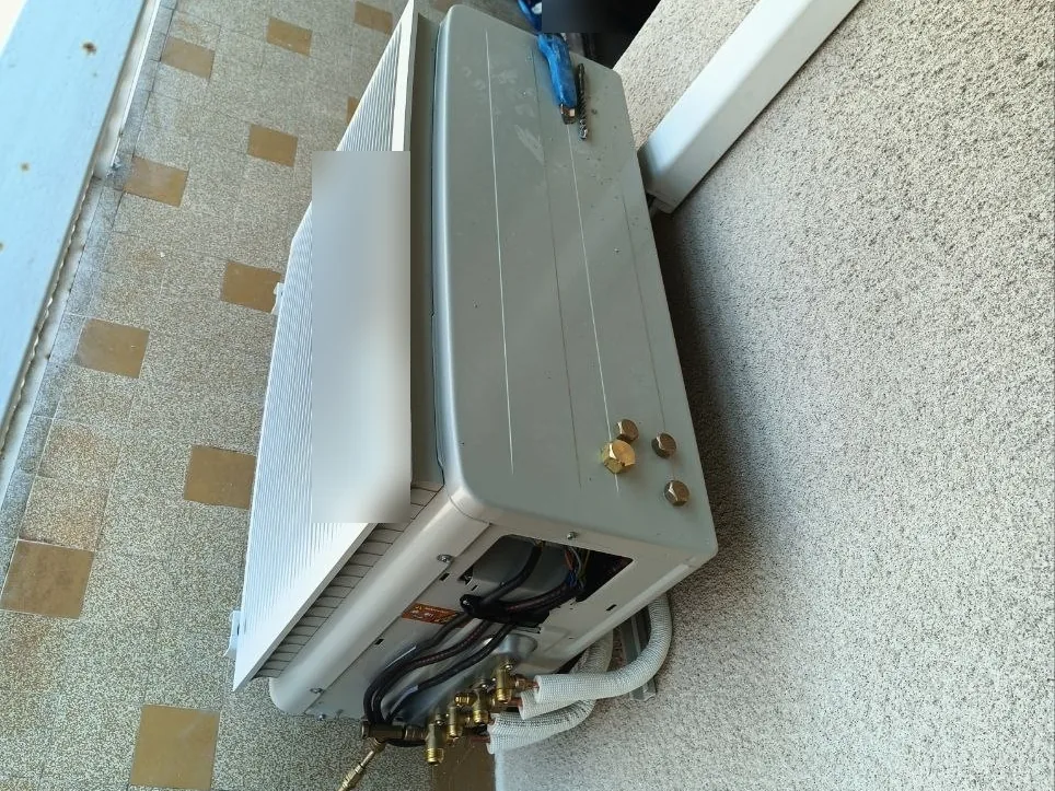 Unité extérieure de climatisation en cours de raccordement sur un balcon